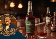 A bottle of Old Forester whiskey with a glass of whiskey on a bar, other bottles blurred in the background, and a cartoon man holding a bottle labeled "Nick's Picks."